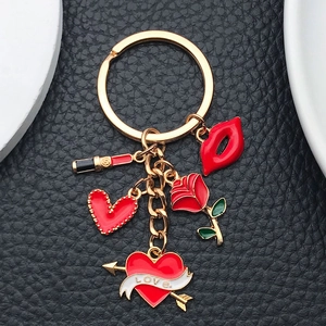 Detail of red lips, rose, and love heart charms on a gold metallic keychain pendant