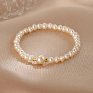 Detailed view of freshwater pearl bracelet with gold beads on smooth satin background