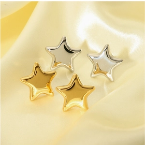 Close-up of gold and silver star earrings resting on elegant yellow silk fabric background