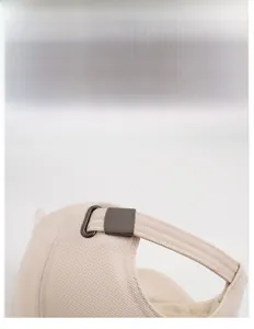 Detail view of the beige baseball cap showing the adjustable metal buckle and knit texture