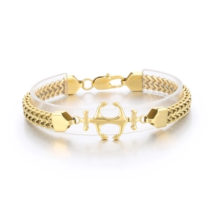 Golden stainless steel Cuban chain bracelet with a central anchor charm on a display stand