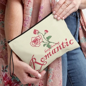 Canvas makeup bag with red rose print and Romantic slogan held by a model