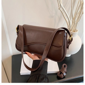 Detail of dark brown leather handbag with gold hardware and extra shoulder strap