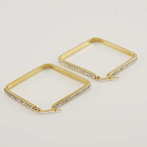 Minimalist square golden earrings with sparkling rhinestones on a grey background
