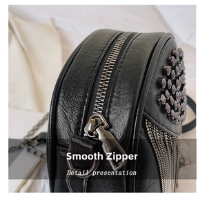 Close-up of smooth silver zipper and tassel detail on black leather crossbody bag