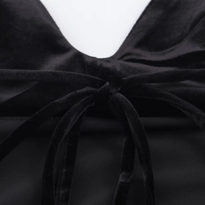 Vue macro de la texture en velours noir et du nœud en dentelle délicat sur la robe midi