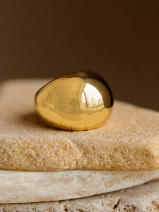 Macro shot of chunky 18k gold plated stainless steel dome ring on natural stones