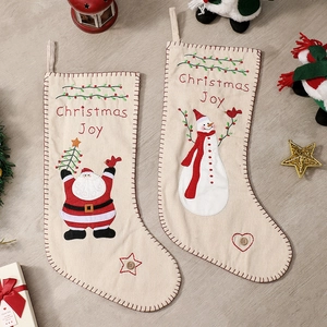 Ethnic style embroidered Christmas stockings with Santa and Snowman on wooden floor