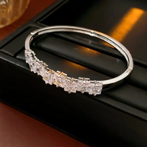 Détail d'un bracelet jonc argenté avec sept zircons carrés sur un support en cuir noir
