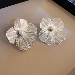 Elegant large metal flower stud earrings with radial texture and center pearl detail