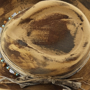 Macro detail of distressed Western cowboy hat with vintage beads and woven fabric band