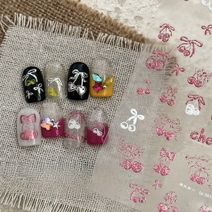 Close-up of glittery cherry and heart nail art stickers with metallic gold accents
