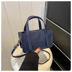 Detail of dark blue crocodile pattern texture on a stylish square PU leather handbag