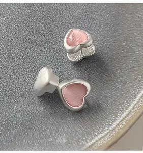 Macro view of pink heart-shaped cat eye stone earrings with silver matte metal frames