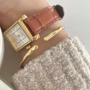 Retro square gold watch with brown leather strap paired with a minimalist open bangle