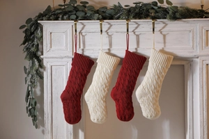 Detail of cable knit Christmas stockings in red and cream hanging on a white mantel