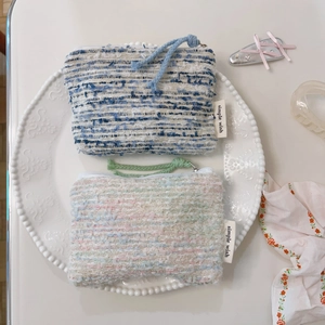 Dettaglio di due mini borse in tweed con etichetta simple wish su un piatto di ceramica