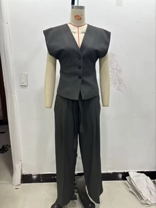 Detail view of dark grey V-neck sleeveless vest and high waist wide leg trousers on mannequin