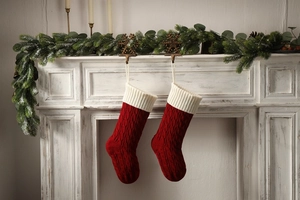 Close-up of red cable knit Christmas stockings hanging on a festive decorated fireplace