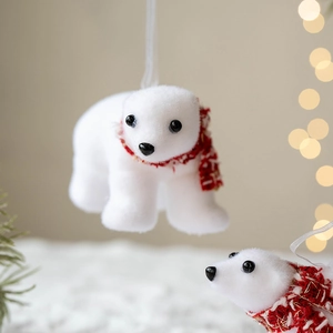 White flocked polar bear Christmas ornament with red scarf on holiday tree branch