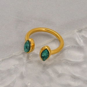 Adjustable gold open ring featuring two marquise green stones on a textured glass base