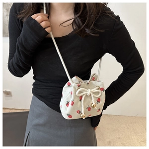Detailed view of white corduroy bucket bag featuring strawberry prints and drawstring