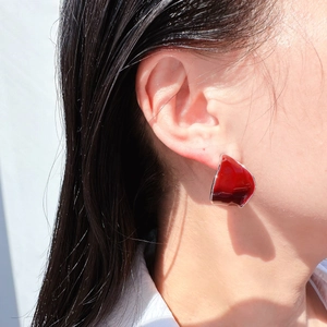 Burgundy red enamel curved leaf earrings on model in professional side view shot
