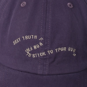Detail of embroidered slogan on deep purple cotton twill baseball cap fabric