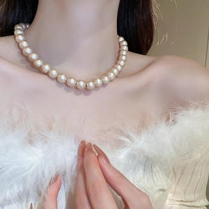 Primo piano di una collana di perle barocche dorate su modella che mostra lucentezza e texture
