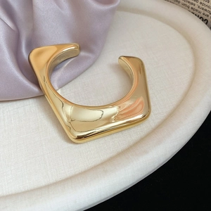 Detailed macro view of the gold irregular geometric bangle with a high-polished mirror finish