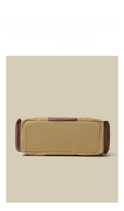 Detail shot of the wide bottom structure of a khaki canvas and brown leather travel bag