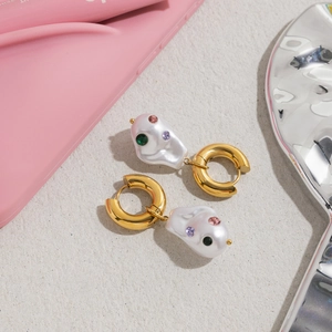 Detail of gold hoops with baroque pearl pendants and colorful inlaid gemstones