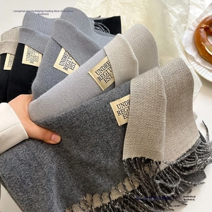 Detailed view of soft cashmere-like scarves with fringe edges and vintage woven labels