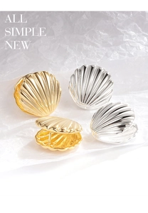 Macro detail of gold and silver shell-shaped earrings with fine radial texture