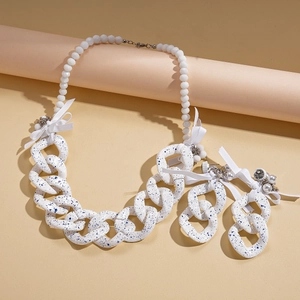 Detail view of chunky acrylic chain necklace with blue ink spots and silk bow accents