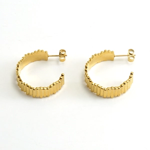 Detail showing gold semi-circle earrings with elegant striped texture on white backdrop