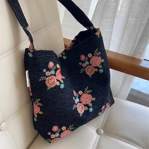 Detail of floral tapestry tote bag with rose embroidery on white leather armchair
