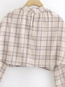 Detail view of plaid cropped top featuring back button closure and elastic hem detail