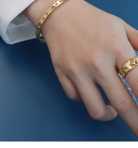 Close-up of gold-plated Roman numeral bangle with diamonds and quilted pattern ring