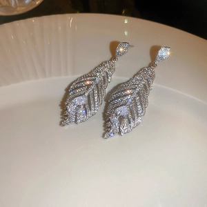 Macro orecchini a piuma in argento con zirconi su vassoio in ceramica bianca