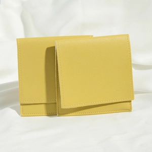 Detailed view of two yellow PU leather jewelry pouches with textured flaps and stitching