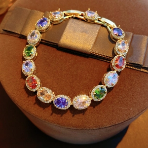Close-up of vintage gold bracelet with colorful oval gemstones and zircon inlay