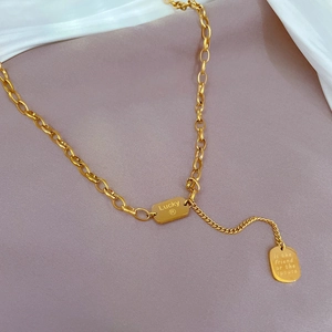 Macro detail of gold-plated titanium steel necklace with Lucky and slogan engraved tags