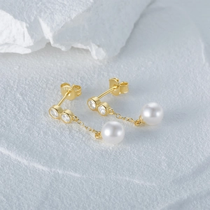 Close-up of golden tassel earrings with sparkling zircons and elegant white pearls