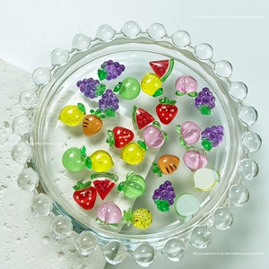 Close-up of 3D resin fruit nail art charms including watermelon and strawberry pieces