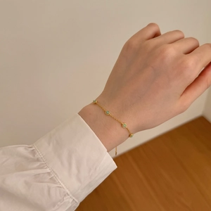 Detailed view of a gold Mobius bracelet with green opal stones worn on a female wrist