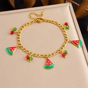 Détail d'un bracelet doré avec des breloques pastèque rouges et un fermoir mousqueton