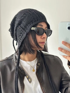 Détails de la maille d'un bonnet au crochet noir avec des lanières tressées décoratives