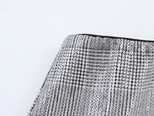 Gros plan sur les paillettes argentées du tissu pied-de-poule gris et blanc
