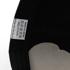 Detail view of the 100% cotton fabric and washing label inside the black baseball cap